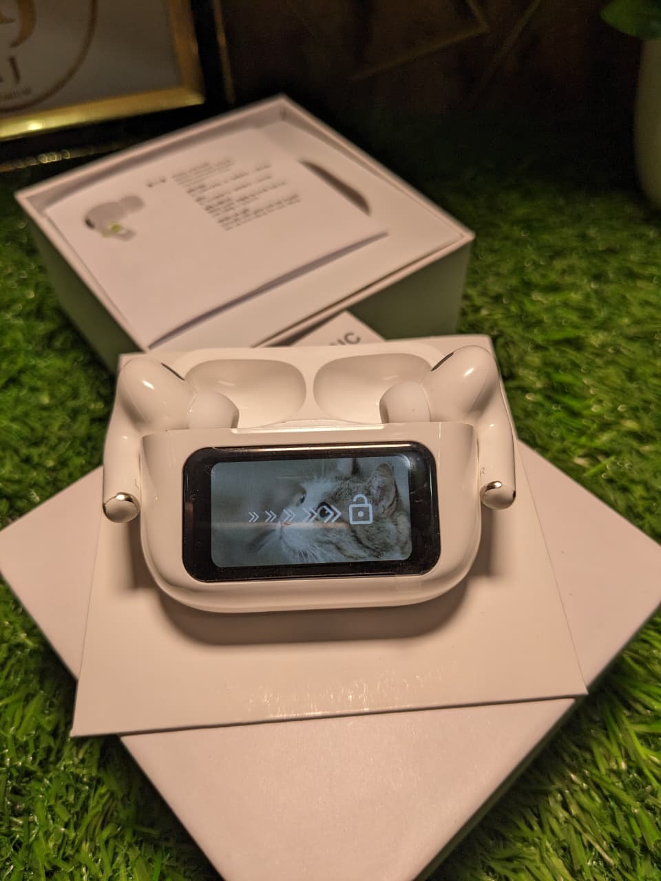 White Buds A9 pro with display device with screen on a grass-like surface