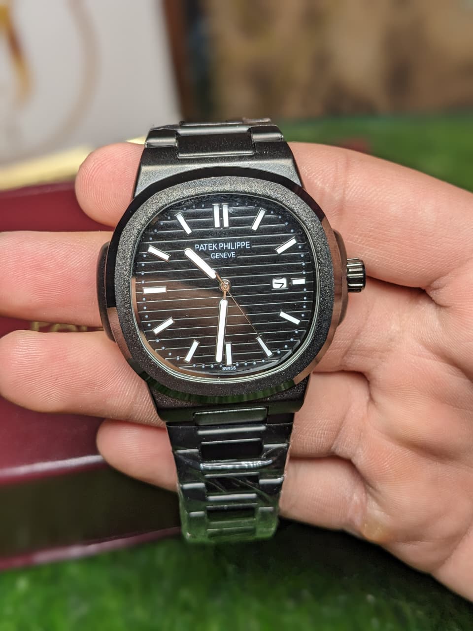 Person holding a Patek Philippe watch with a blurred background