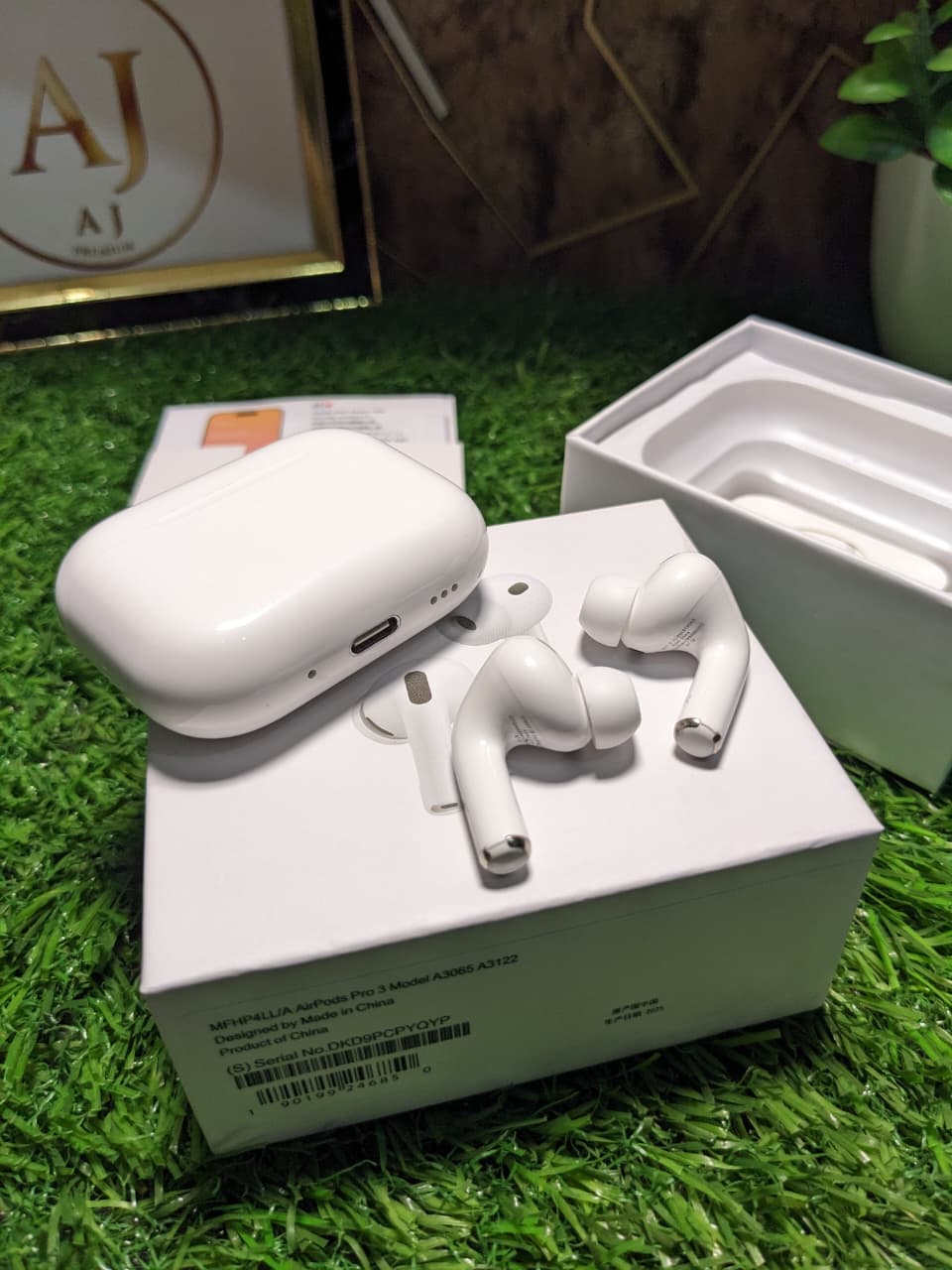 White wireless earbuds Apple earbuds pro 3 with charging case on a grass-like surface.