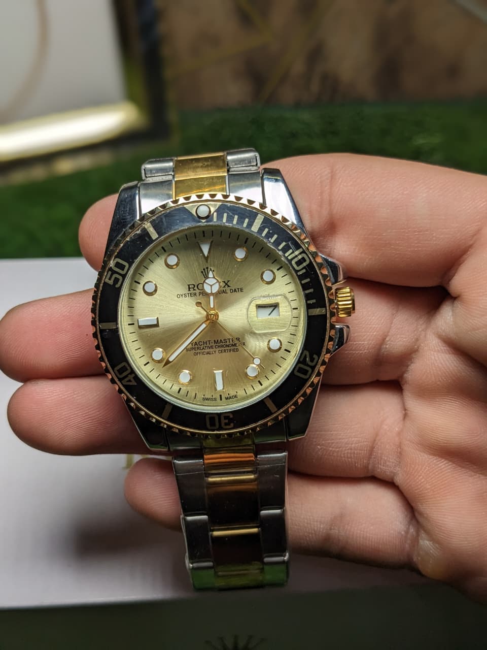 Gold and silver luxury  watch held in a hand with a blurred background