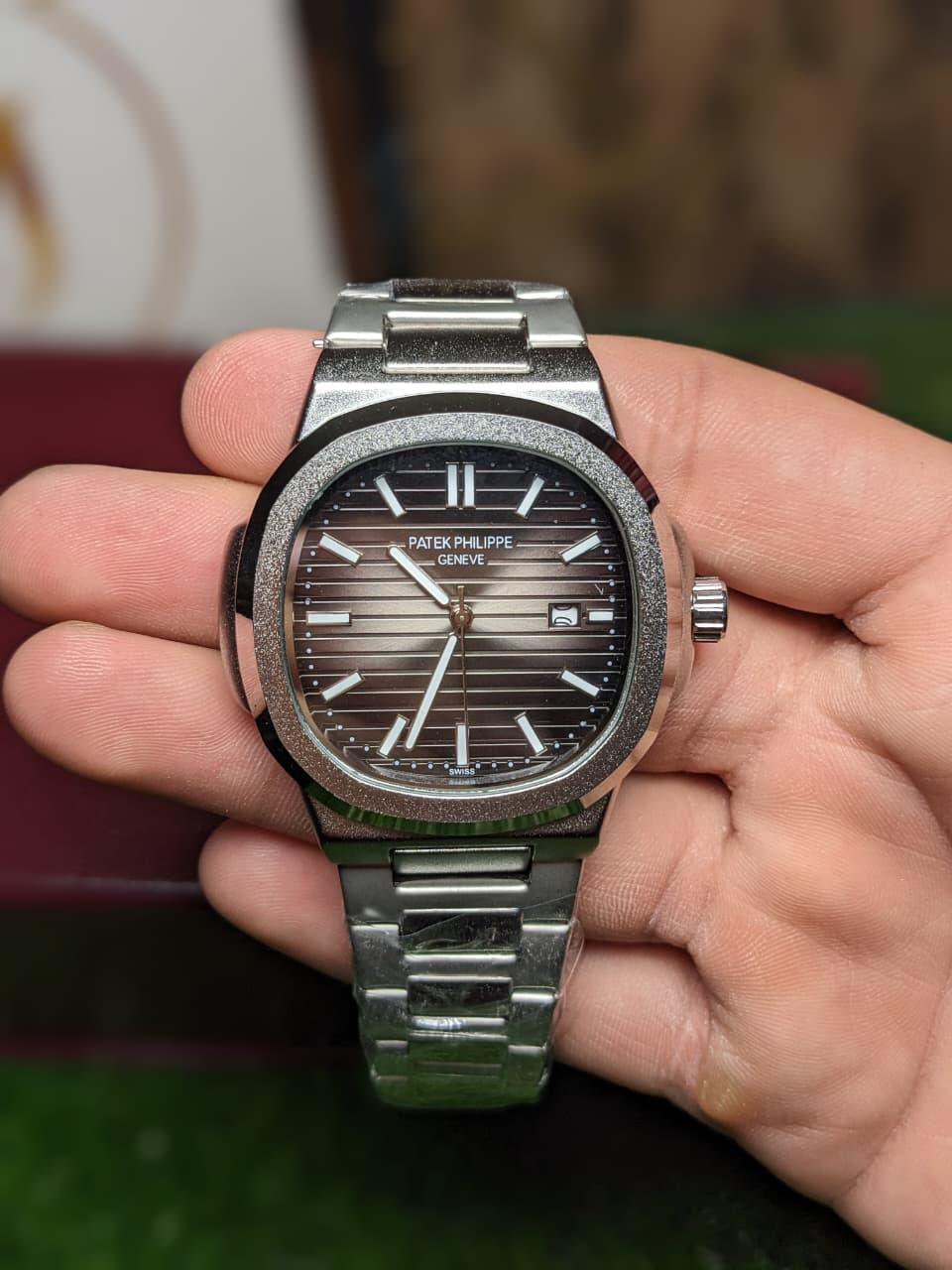 Silver Patek Philippe  luxury premium watch held in a hand with a blurred background