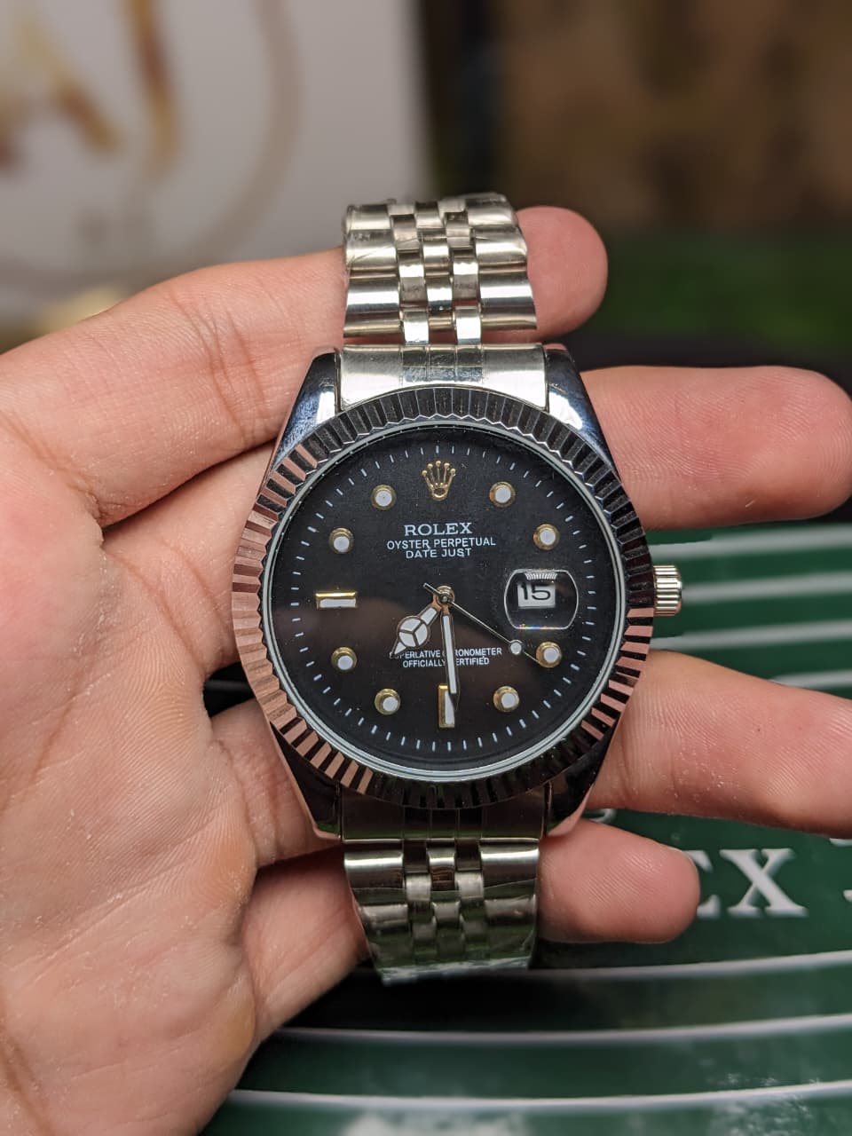 Hand holding a silver and black Rolex luxury premium watch with a blurred background