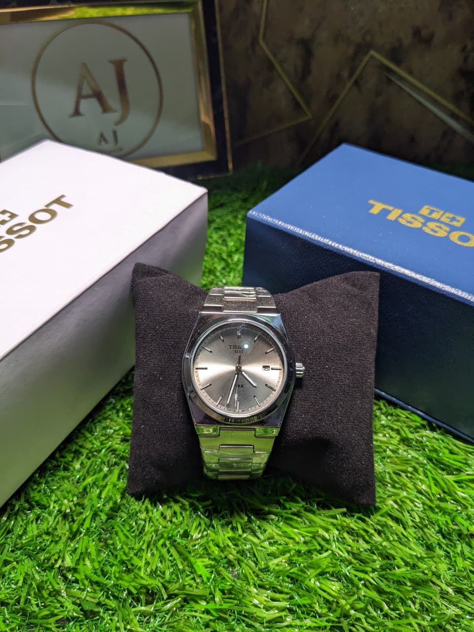 Silver Tissot luxury premium watch on a black cushion with grass background