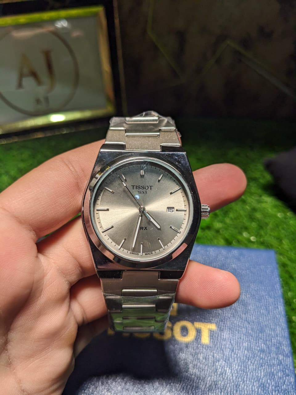 Silver Tissot luxury premium watch held in a hand with a blurred background