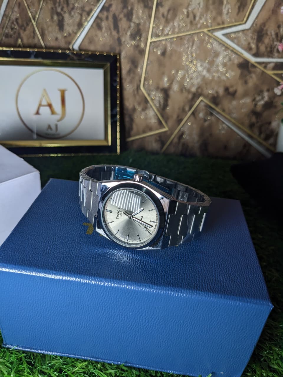 Silver watch on a blue box with a decorative background