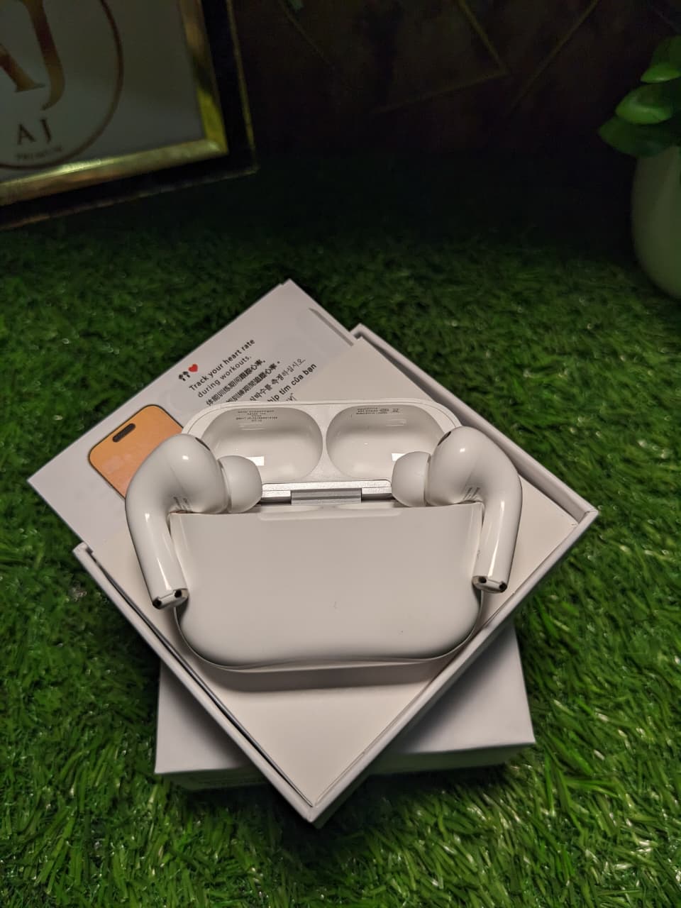 Wireless earbuds Apple Airpods pro 3 in a charging case on a grass-like surface with a blurred green background