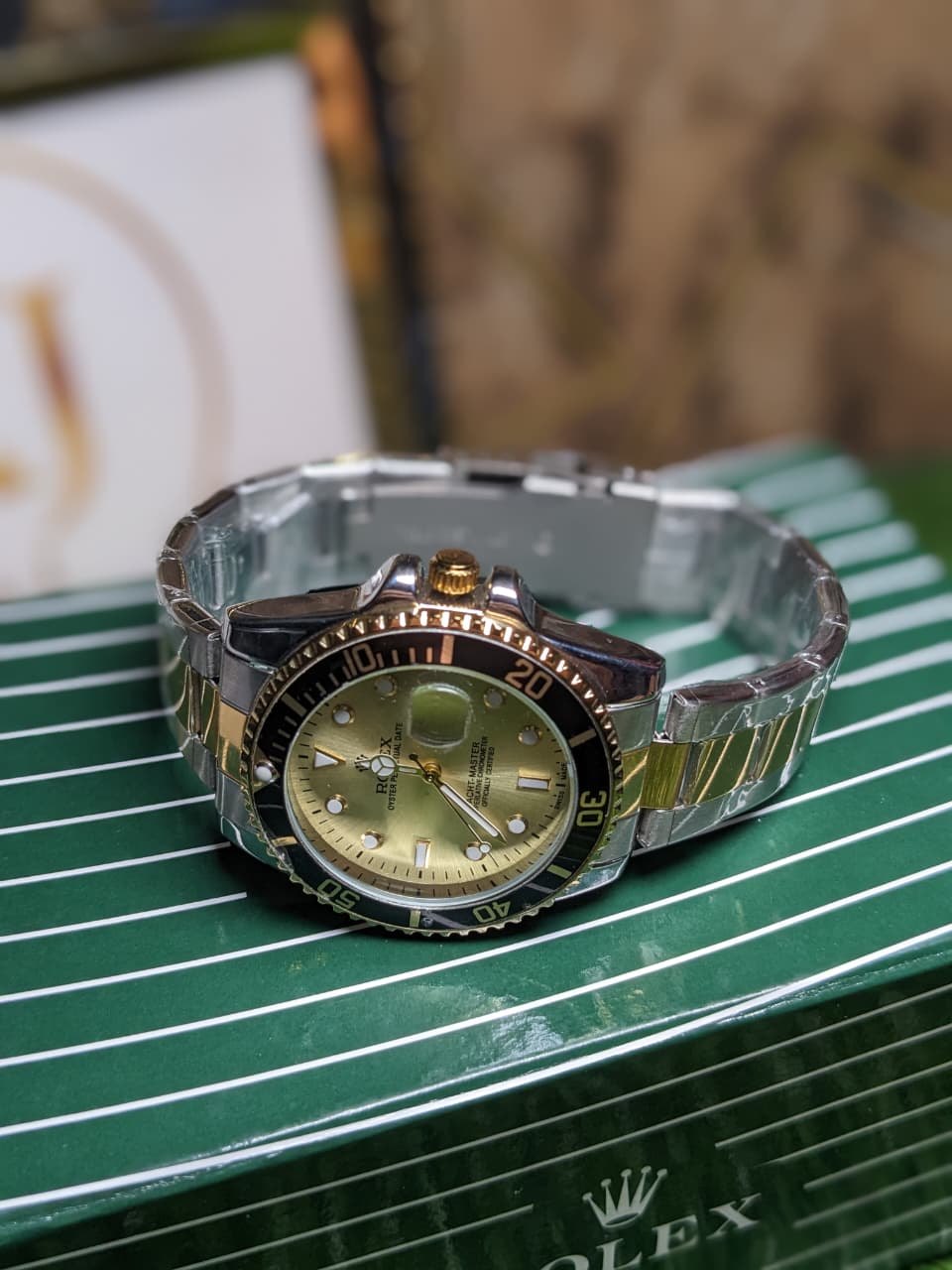 Rolex watch with a clear and gold band on a green surface
