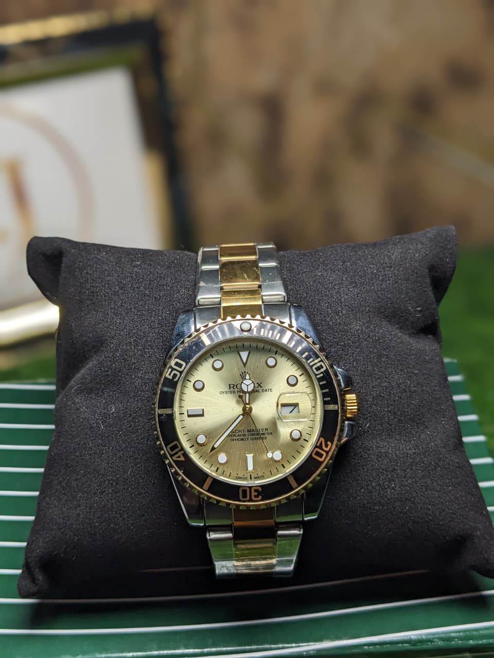 Gold and silver watch on a black cushion with a blurred background
