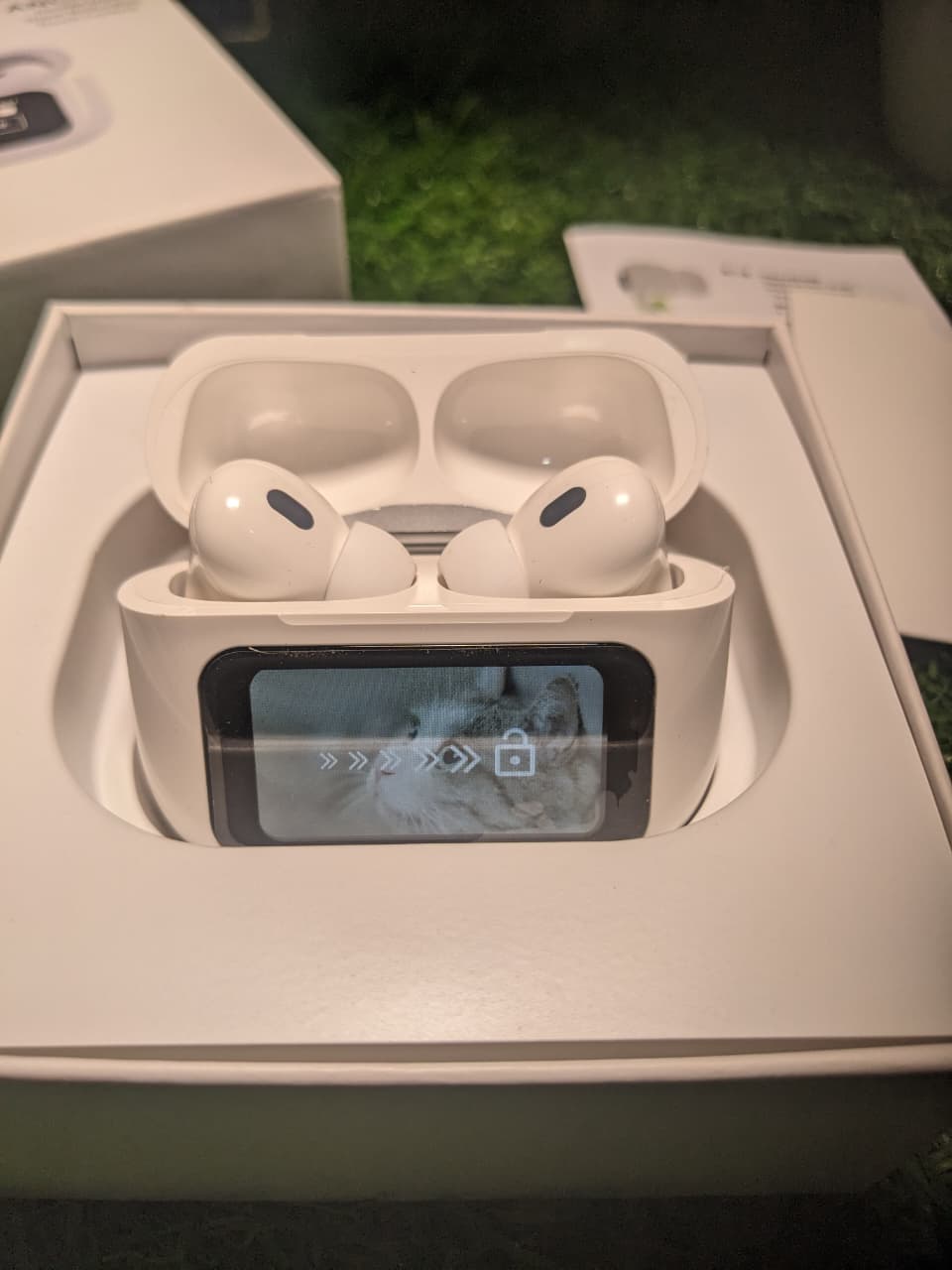 Wireless earbuds in a charging case with a digital display, inside an open box.