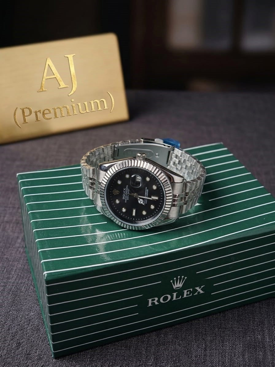 Silver luxury  watch with black dial on a green Rolex box with 'AJ (Premium)' card in the background